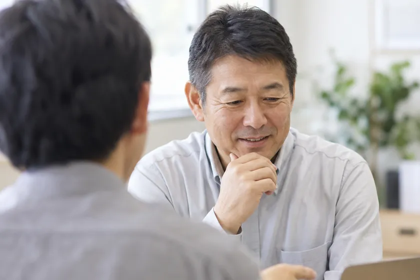 事務所を訪ね、依頼主と並んでノートパソコンの画面を確認している様子